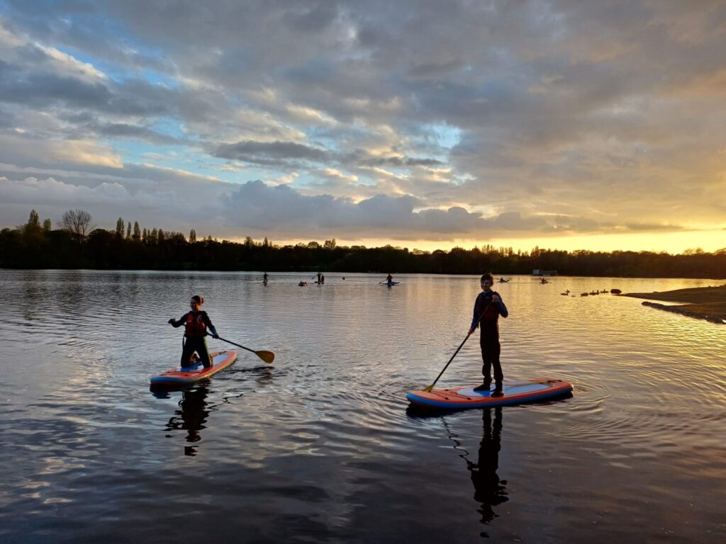 two Sutton Coldfield Sea Scouts on paddle boards at sunset